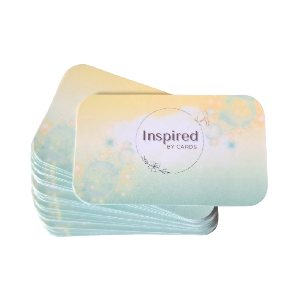 Een stapel affirmatiekaarten voor ouders of positief ouderschap met afgeronde hoeken. De bovenste kaart heeft een ontwerp met een lichte pastelkleurige achtergrond. De tekst op de bovenste affirmatiekaart positief opvoeden is: "Inspired by Cards", van het merk More2Inspire.