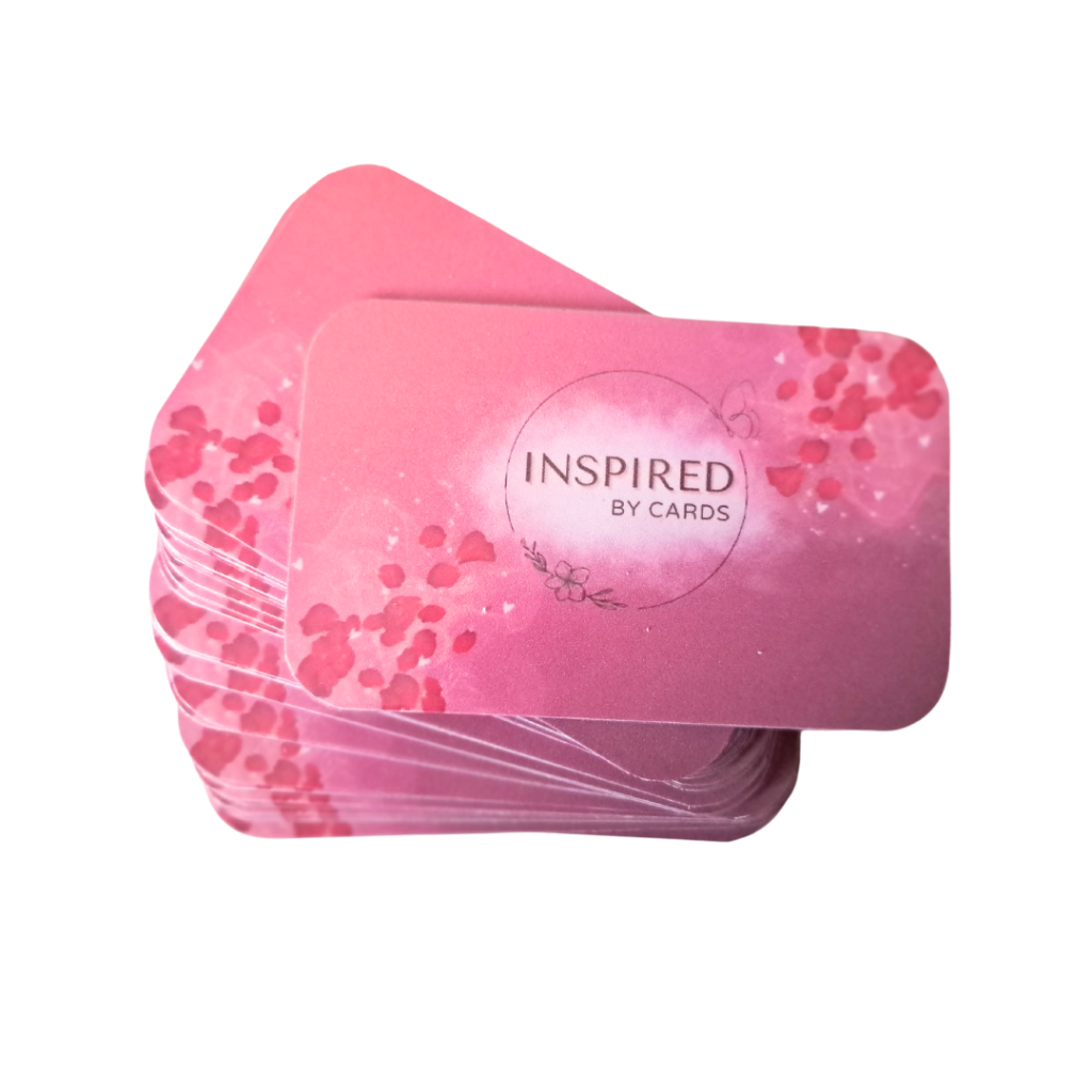 Stapel roze inspirerende affirmatiekaartjes met afgeronde hoeken en de tekst ´inspired by cards` in het midden, omringd door een subtiel bloemenpatroon.