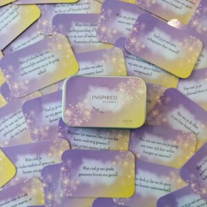 Een collectie van vraag- en opdrachtkaarten gezin ter bevordering van de interactie en verbinding binnen het gezin. De kaartjes hebben de kleuren paars en goud en afgeronde hoeken. In het midden is een kaartendoosje geplaatst met de tekst Inspired by Cards erop. Op de gezinsvraagkaarten eromheen zijn voorbeelden te zien van vragen en opdrachten die in de kaartenset zitten.